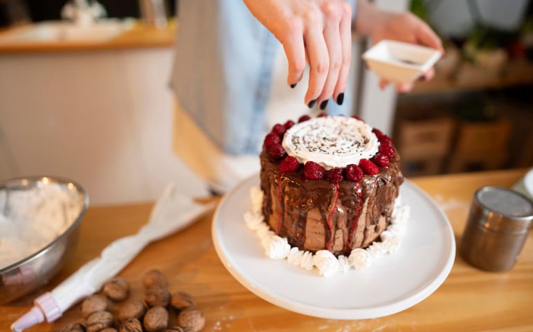 An unrecognizable woman decorating a cake she made at her kitchen.