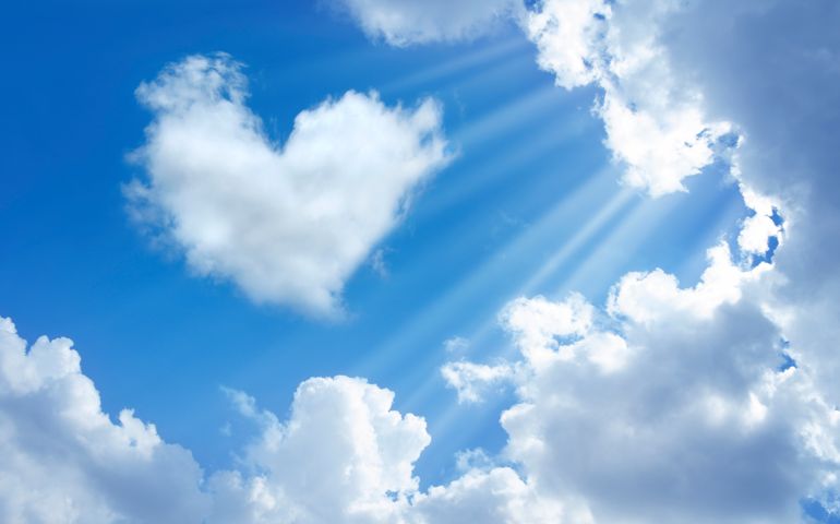 heart shaped cloud in cloudy sky and sunbeam.
