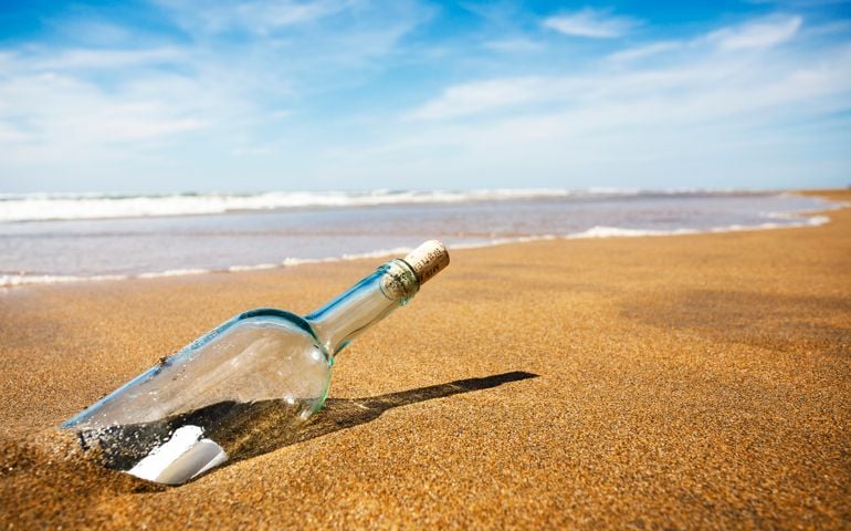 A clear glass bottle washed up on the beach, with a note inside