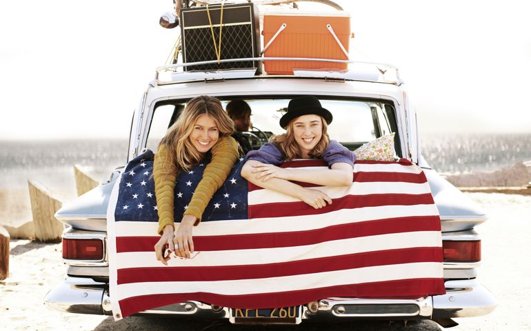 Two girls smiling from the back of a car.