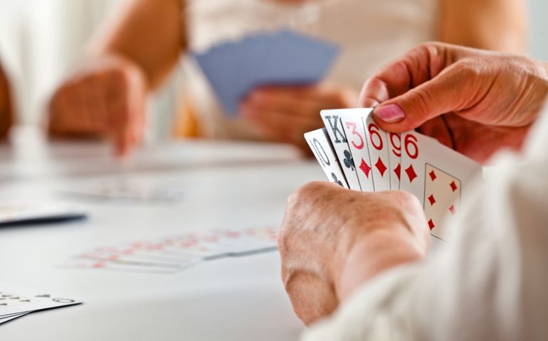 Focus on senior woman's hand holding cards during cards game.