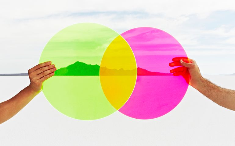 Two hands holding colored circles in landscape.