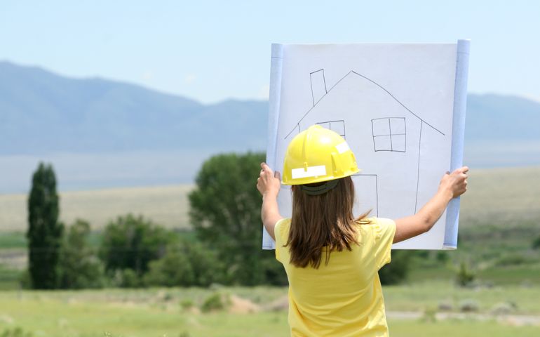 little girl holding house plans over a majestic landscape