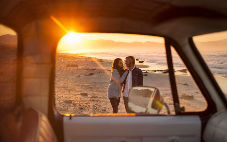 Couple walking on beach by truck
