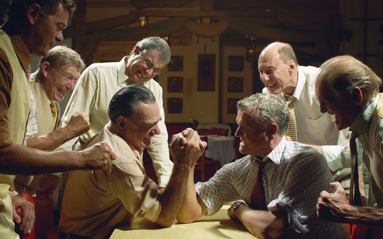 Group of men watching two men arm wrestling