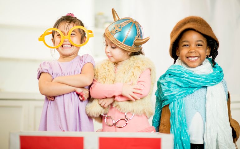 Little girls dressed in theatrical costume laughing and smiling together.