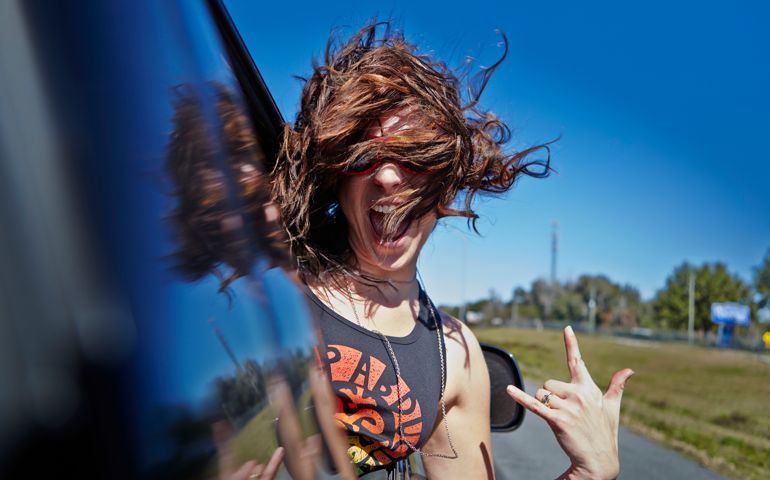 Young woman hanging out car window