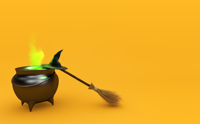 Boiling witch's cauldron with hat and broom isolated on orange background.