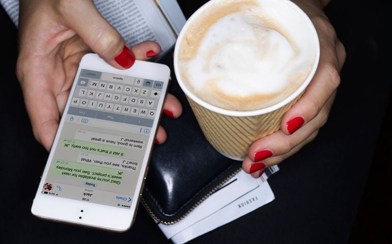Female holding take away coffee, texting, close up