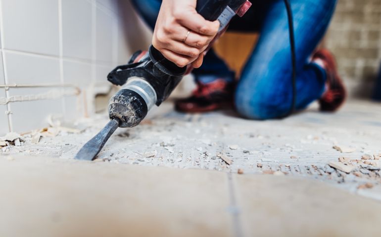 Woman removing old tiles, renovating the bathroom.