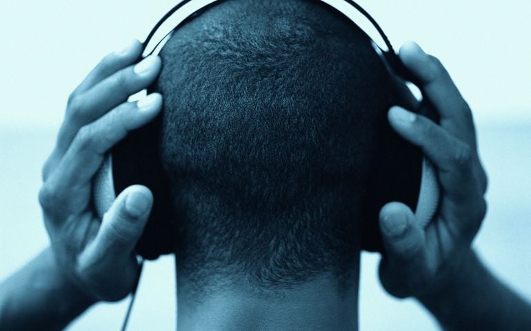 Young man wearing headphones, rear view, close-up (B&W)