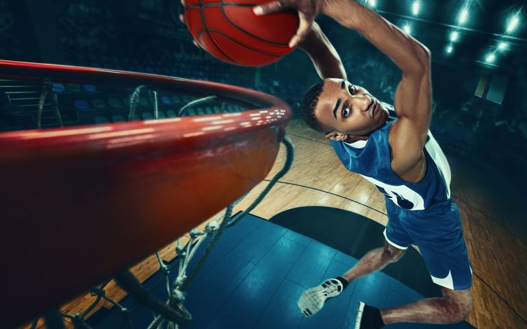 An African man basketball player jumping with ball on black background