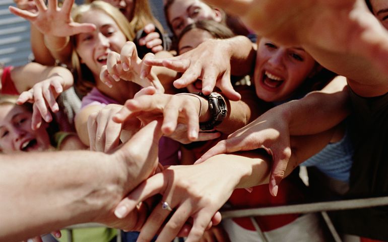 Hand of star extended to excited teenage girls