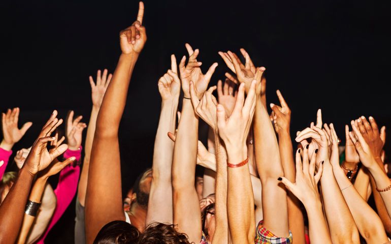 Large crowd with hands and fingers pointing up, excited