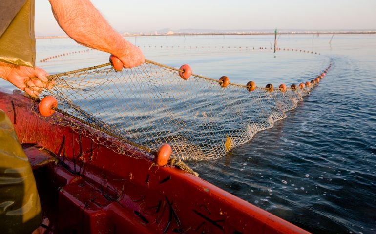 fisherman pulling in the nets on boat at sea