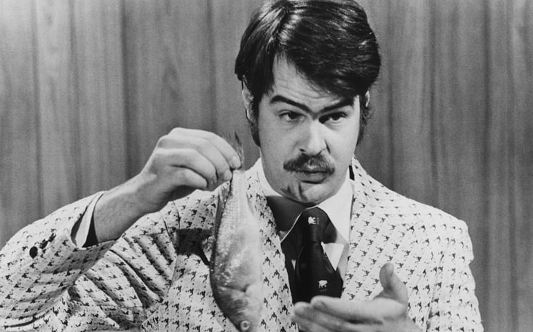 Canadian-American comedian Dan Aykroyd prepares to demonstrate the 'Super Bass-O-Matic' on a sketch from the TV comedy show 'Saturday Night Live', 1976
