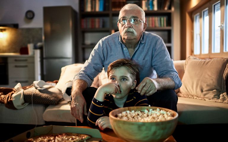 Close up of a grandfather watching a movie with his grandson