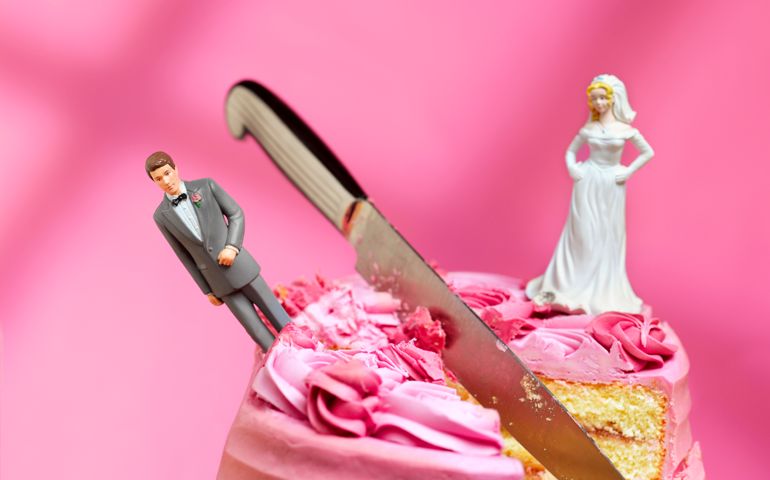 knife cutting between bride and groom figurines, relationship breakup