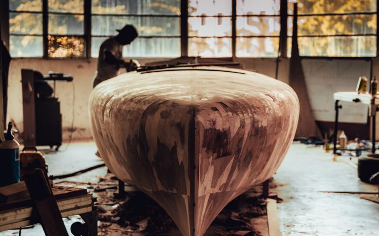 Man sanding wooden power boat building project