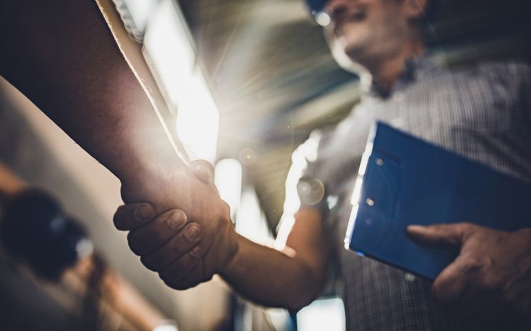 Low angle view of manager greeting unrecognizable person in industrial building.
