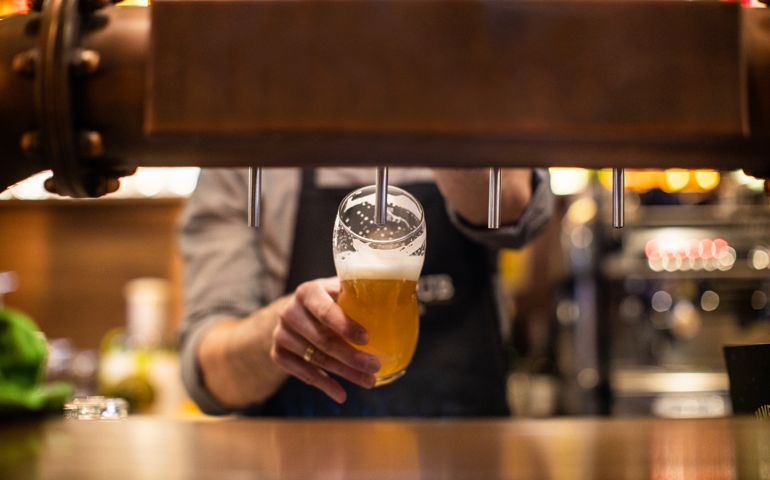 Unrecognizable man pouring a beer on beer tap in drinking glass, in a pub