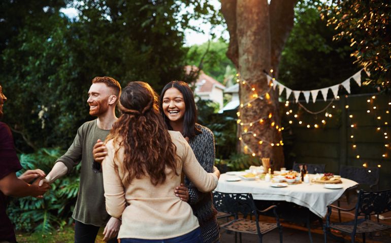 Shot of young friends greeting each other at a dinner party outdoors