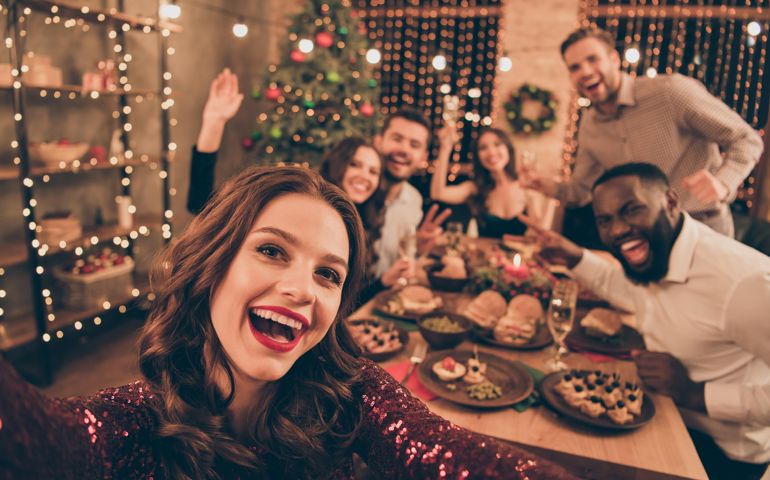 Close up photo of cheerful fellows in formal wear sit around table enjoy, christmas party x-mas holidays making selfie in house full of noel decoration