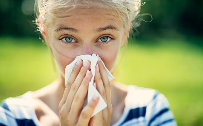 Portrait of teenage girl blowing her nose on a summer day. The girl is allergic to the pollen. Nikon D850