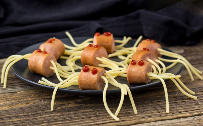 spaghetti with sausages in the form of spiders. Happy kid food for Halloween party on wooden background