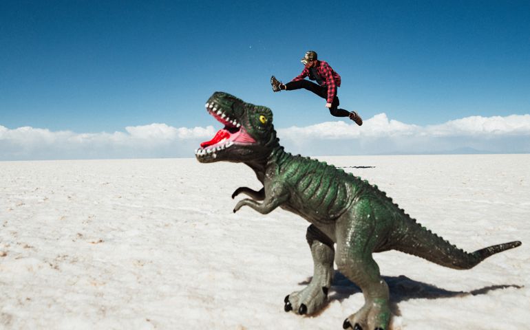Fun forced perspective shot of young man whos trying to fight with dinosaur at Uyuni Salt Flats (Spanish: Salar de Uyuni ) in Bolivia, South America.
