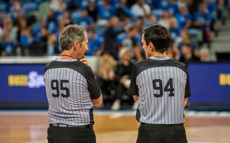 Rear view of referees standing on court in stadium.