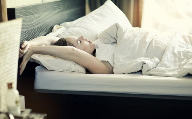 Young woman waking up in bed