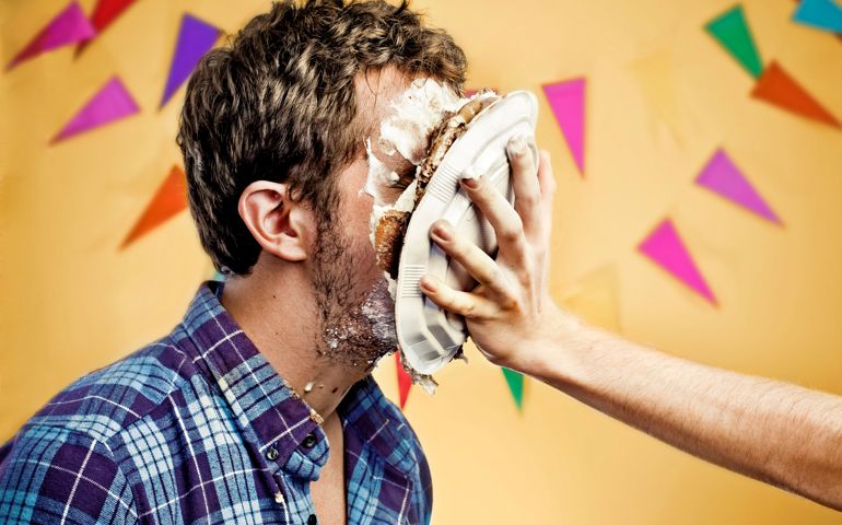Young man with cake on face