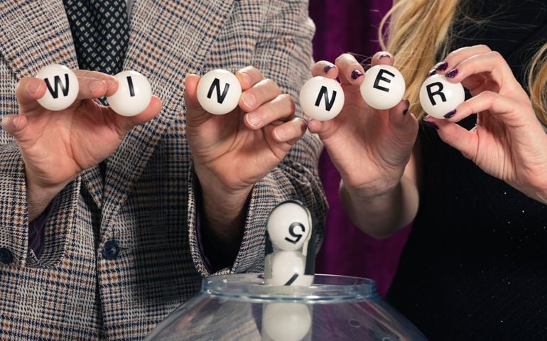 A Retro color processed lottery drawing show and assistant host holding balls spelling WINNER. Photographed in studio with a purpose built set and props.