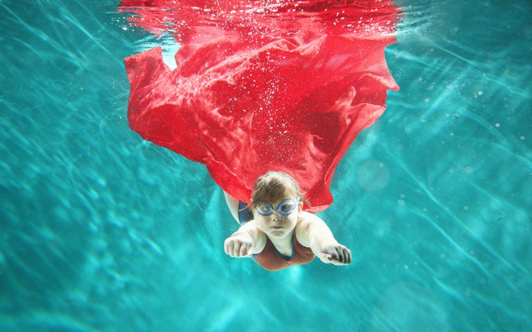 Small girl as superhero flying underwater