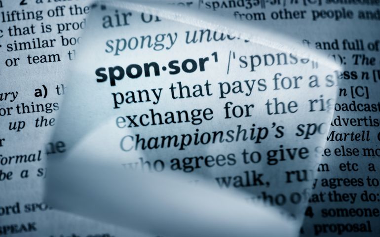 The Dictionary definition of the word “sponsor” photo taken through magnifying glass from a page of a dictionary with selective focus.