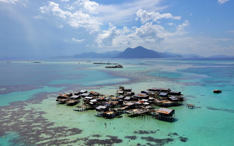 A Bajau floating village of stilted houses built in turquoise waters on a tropical coral reef at sea off the coast of Borneo Island. The Bajau Laut (also called Badjao people) or sea dwelling Bajau are nomadic sea gypsies ( Sami di Laut ). Location: Off the coast of Borneo in The Celebes Sea in the vicinity of Sipidan and Tun Sakaran Marine Park, also called the Semporna Islands Park. Sabah, Malysia.