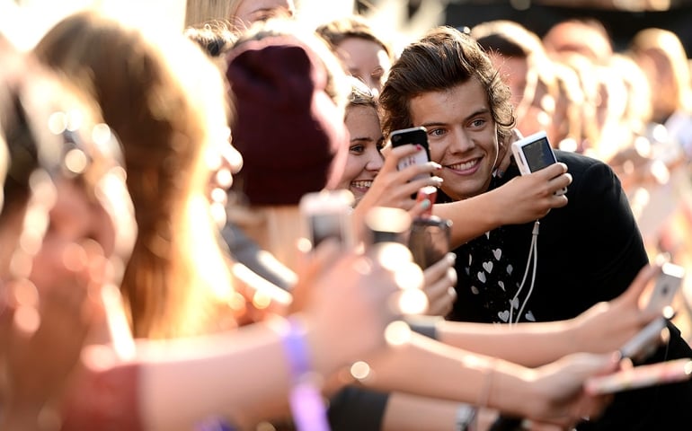 LONDON, ENGLAND - AUGUST 20: Singer Harry Styles from One Direction poses with fans as he attends the "One Direction This Is Us" world premiere at the Empire Leicester Square on August 20, 2013 in London, England.
