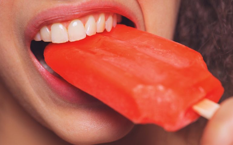 Young woman eating popsicle, close up