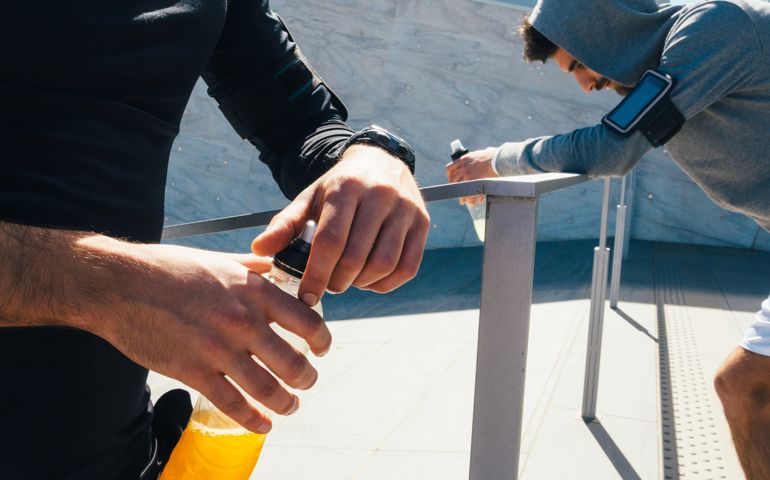 Friends Resting And Drinking An Energy Drink While Training