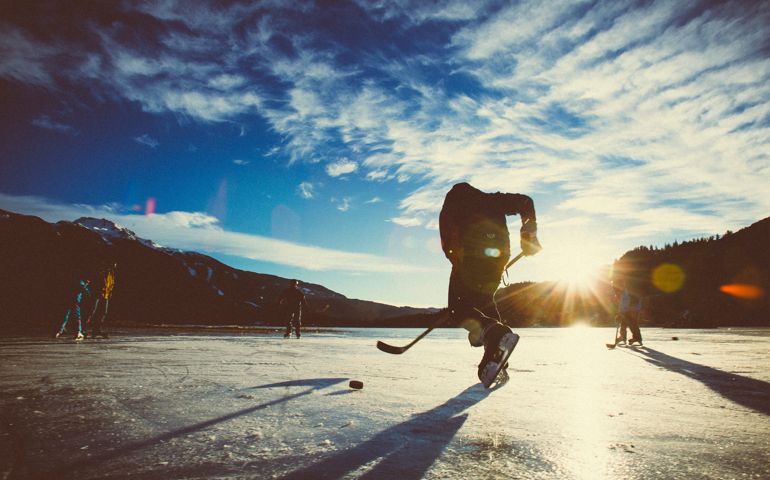 Man silhouette skating with hockey stick and playing with puck.