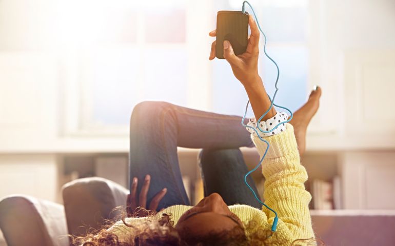 Woman relaxing at home listening to her phone.