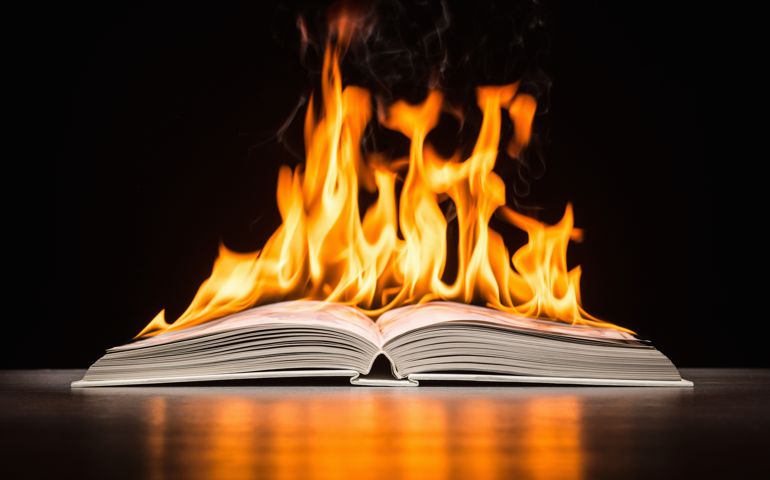 Open hard covered book engulfed in flame