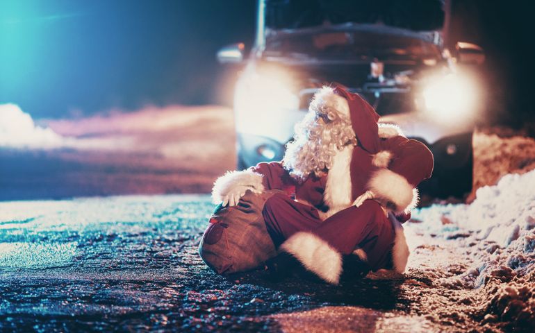 It's Christmas eve and this modern Santa Clause is having trouble with his car in the middle of snowy nowhere. He's trying to deliver presents for the good ones. He's sitting on the road in front of the car and desperately waiting for someone to pass by. Front view, low angle shot.