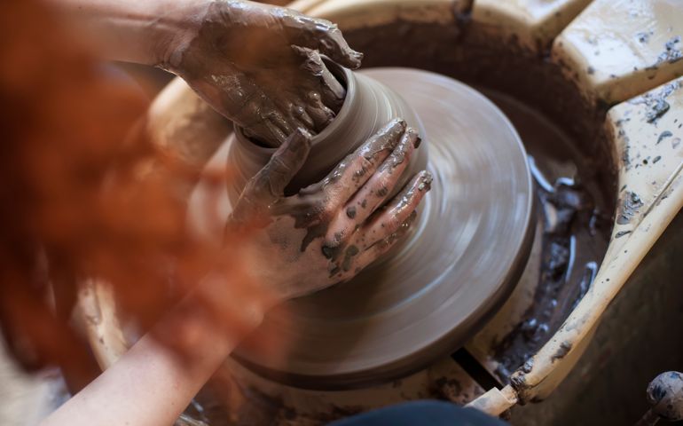 Human hands working on pottery wheel, close up