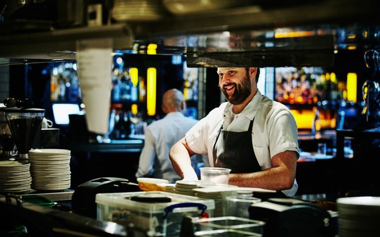 Smiling chef preparing dinner ingredients at workstation in restaurant kitchen