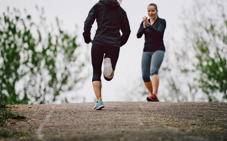 Women running together uphill in a park