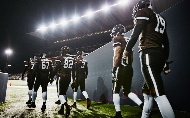Professional football team walking out of stadium tunnel onto field for night game