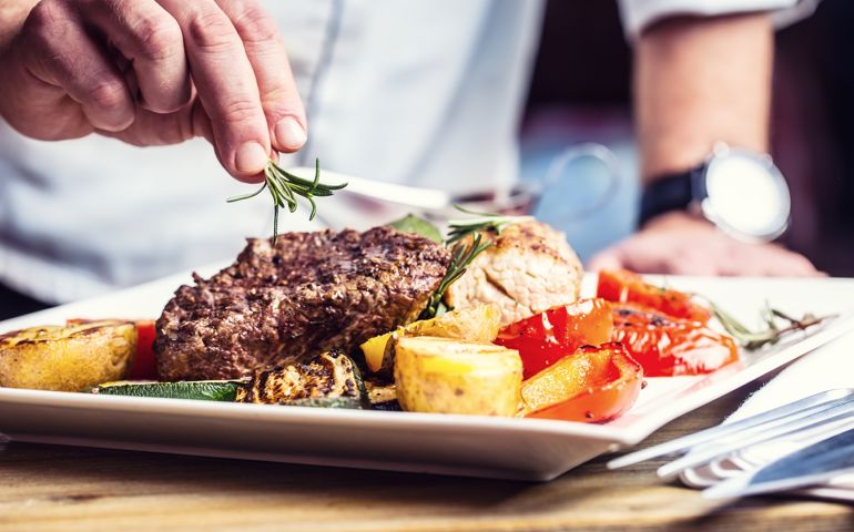 Chef in hotel or restaurant kitchen cooking only hands. Prepared beef steak with vegetable decoration.Chef in hotel or restaurant kitchen cooking only hands. Prepared beef steak with vegetable decoration.