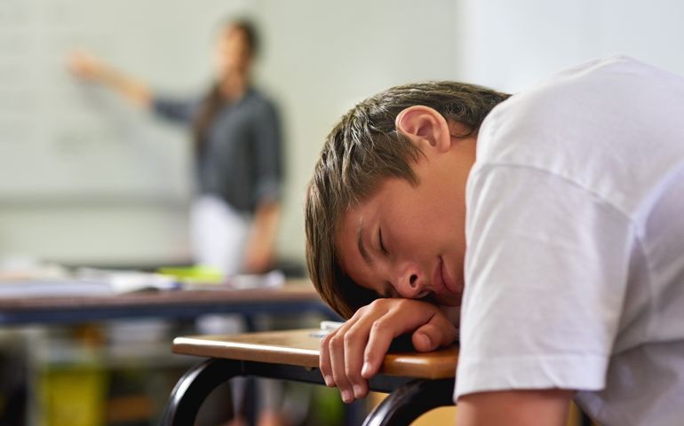 Shot of a young schoolboy sleeping on his desk in class